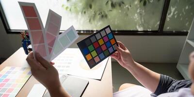 Graphic designer analyzing color palettes and samples at a creative workspace. photo