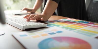 Graphic designer working on a computer keyboard with color charts at a creative desk. photo