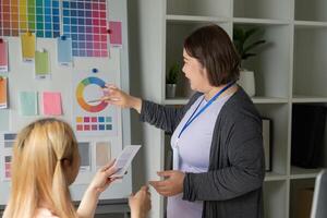 Diverse graphic designer presenting color palette options to a colleague. photo