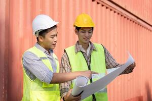 Logistics engineer pointing at plans while discussing with a colleague. photo