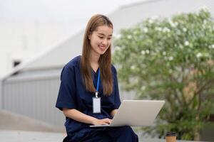 Nurse enjoying a break while working on a laptop for patient care and documentation photo