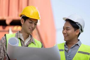 Logistics engineer and colleague smiling while reviewing construction plans. photo