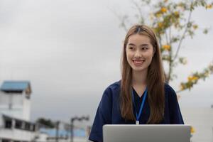 Nurse smiling while using a laptop for patient care and documentation during a break photo