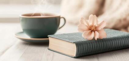 book about holistic healing rests beside steaming cup of tea, adorned with delicate flower, creating serene and calming atmosphere photo