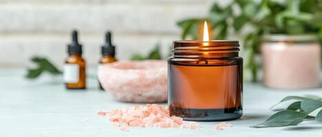 warm amber candle burns brightly, surrounded by pink salt and essential oil bottles, creating calming atmosphere perfect for relaxation and self care photo