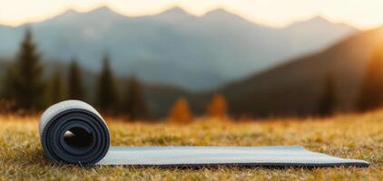 serene yoga mat lies on grassy field, surrounded by majestic mountains and warm sunset glow. This peaceful scene invites relaxation and mindfulness photo