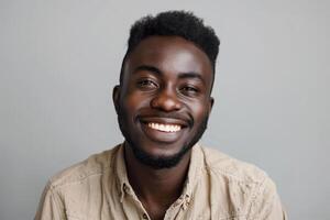 A young man with a bright smile sits against a gray background, dressed in casual attire, exuding happiness and warmth in a relaxed studio environment photo