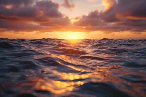 The sun sets over the horizon, casting warm golden reflections on the water. Gentle waves roll in, creating a serene atmosphere during evening twilight photo