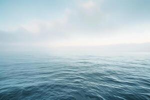 The ocean stretches endlessly under a soft, cloudy sky at dawn, with gentle waves lapping quietly, creating a peaceful and serene environment photo