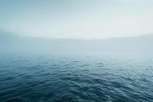 The serene seascape features gentle waves reflecting the soft hues of dawn, enveloped in a mist that creates a peaceful atmosphere over the water photo