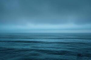 The tranquil ocean stretches out beneath a moody, cloud-covered sky, inviting peaceful reflection during the serene twilight hour as colors blend softly photo