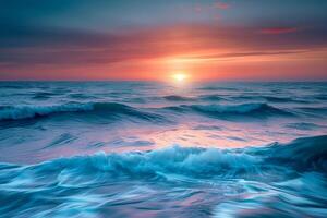 Waves gently roll towards the shore as the sun sets on the horizon, casting colorful reflections across the ocean's surface while the sky transitions to twilight photo