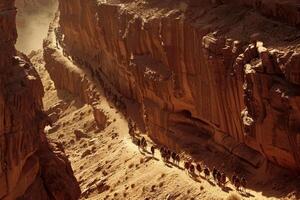 A group of people are walking down a narrow path in a desert photo