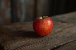 A single red apple sitting on top of a wooden table photo