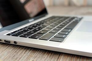 The keyboard of a modern laptop is displayed prominently on a wooden desk, highlighting its elegant design and functionality. The device appears ready for use photo