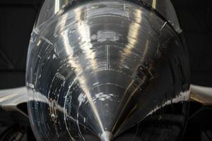 The polished nose of a jet aircraft gleams under the hangar lights, highlighting its aerodynamic design and detailed craftsmanship, emphasizing engineering precision photo