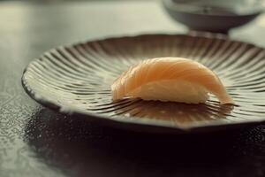 A delicate piece of sushi is elegantly placed on a textured plate, showcasing its freshness and craftsmanship during a calm late afternoon dining experience photo
