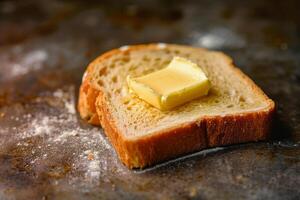 A slice of freshly toasted bread sits on a rustic kitchen counter, topped with a pat of butter slowly melting. The kitchen has a warm, inviting atmosphere photo
