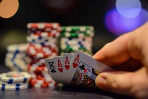 A player holds a winning hand of three aces and a royal flush, surrounded by colorful poker chips on a casino table during a nighttime game photo
