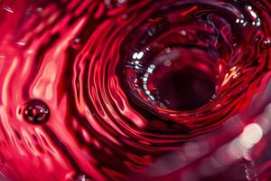 A vibrant red liquid spirals in a circular motion, creating mesmerizing reflections and patterns. The textures and hues showcase fluid dynamics beautifully photo