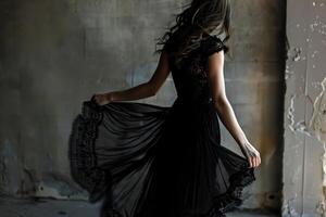 A woman gracefully twirls in a flowing black dress, her silhouette casting intriguing shadows in an empty, rustic indoor space illuminated by soft evening light photo