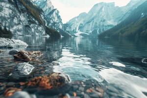 A peaceful lake reflects the imposing mountains, with a rocky shore in the foreground. The calm waters create a serene atmosphere enhanced by the surrounding nature photo