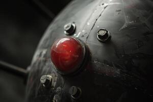 The striking red button is prominently featured against a textured metallic backdrop adorned with several bolts, showcasing industrial aesthetics in low light photo