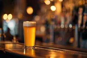 A refreshing glass of golden beer with a foamy top rests on a polished wooden bar. Ambient lighting creates a warm and inviting atmosphere, perfect for socializing photo