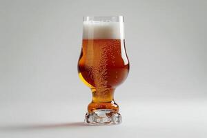 A tall, elegant glass holds a refreshing amber beer with a thick, frothy head. Bubbles rise to the top, creating a visually appealing drink on a matte white background photo