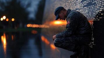 A soldier kneeling down in front of the vietnam memorial photo