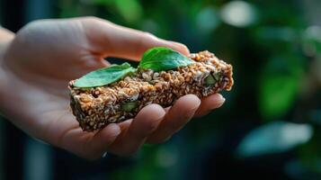 A hand holding a piece of food with a green leaf on it photo
