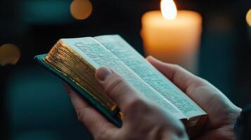 A person is holding a book and a candle photo