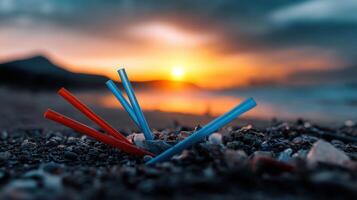 A pile of plastic straws on a beach at sunset photo