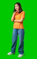 Young woman in orange shirt poses confidently with green background in a creative indoor setting photo