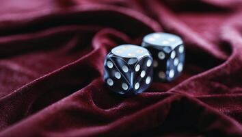 Black dice resting on luxurious red velvet fabric showcasing a game likely in progress during an evening gathering photo