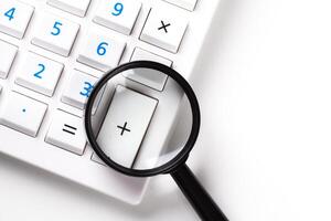 Calculator with a magnifying glass on a white background photo