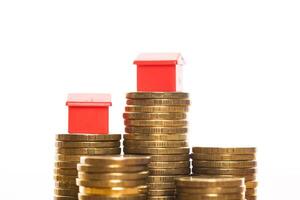 Stacks of coins, green and red home. Mortgage concept by money house from coins photo