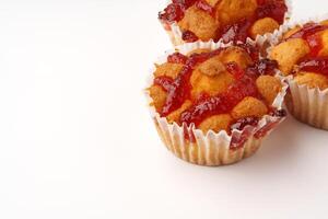 Delicious homemade muffins topped with jam and nuts on a plain background photo
