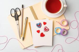 Crafting a heartfelt card with colorful paper hearts, scissors, and drinks in a cozy workspace photo