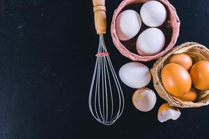 eggs and whisk on a black background photo