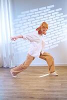Dancer performing dynamic movement in a spacious studio with soft lighting during a creative practice session photo