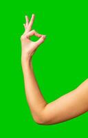 Hand gesture representing approval against a bright green background during a creative project photo