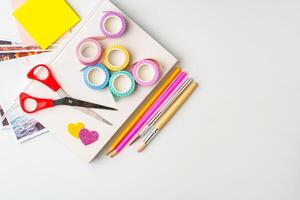 Crafting supplies arranged for creative projects on a light background with scissors, colorful tape, and various pens photo