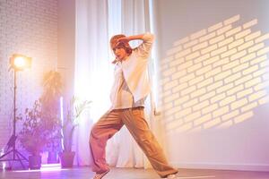 Dancer in stylish clothing performs an expressive routine in a well-lit studio with modern decor during an afternoon session photo