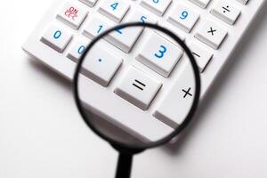 Calculator with a magnifying glass on a white background photo