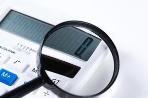 Calculator with a magnifying glass on a white background photo
