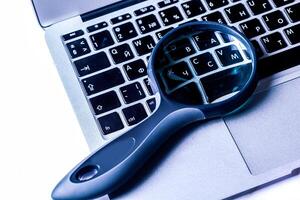 Closeup images of magnifying glass on laptop keyboard photo