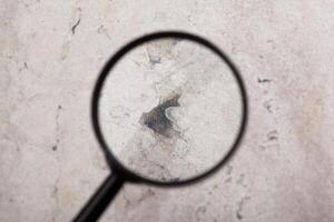 Magnifying glass with empty stone background. photo