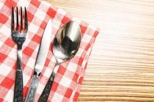 Fork and table knife on red gingham tablecloth photo