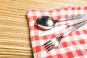 Fork and table knife on red gingham tablecloth photo